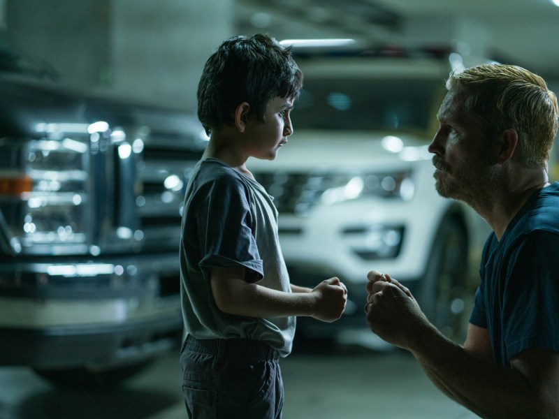 A still from the movie 'Sound of Freedom' shows a man kneeling and staring into the eyes of a young boy.