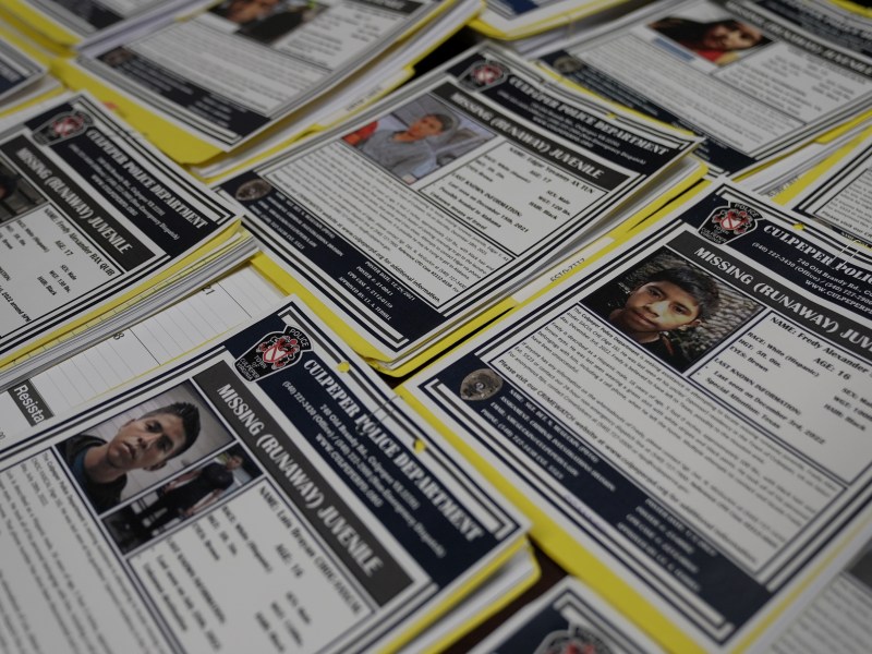 Several missing migrant children posters are displayed across a table.