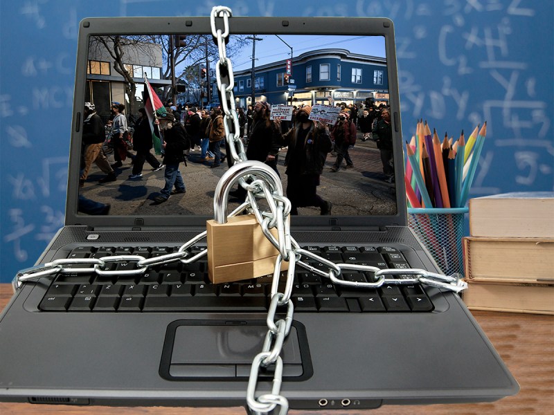 A laptop with a photo of a protest on its screen is shown with chains around it and a lock.